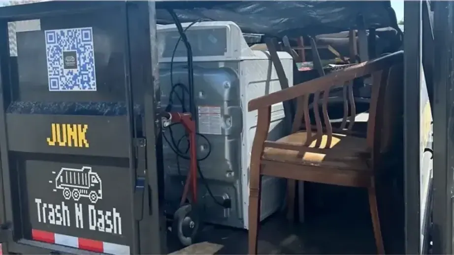A washer and wooden chairs loaded in the back of the Trash N Dash trailer