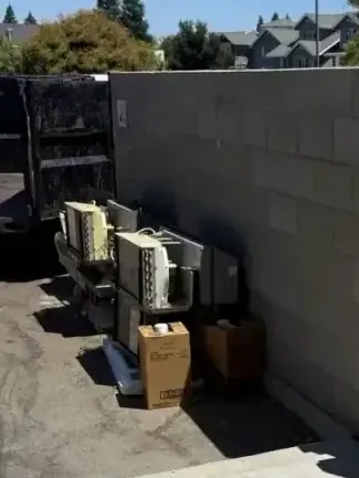 Old window air conditioners boxes and a pallet stacked against a block wall