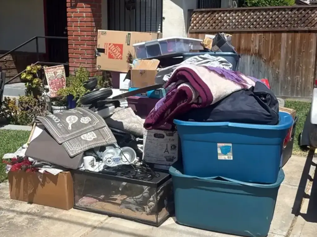 Bins boxes and household goods piled on a front walk beside a brick house