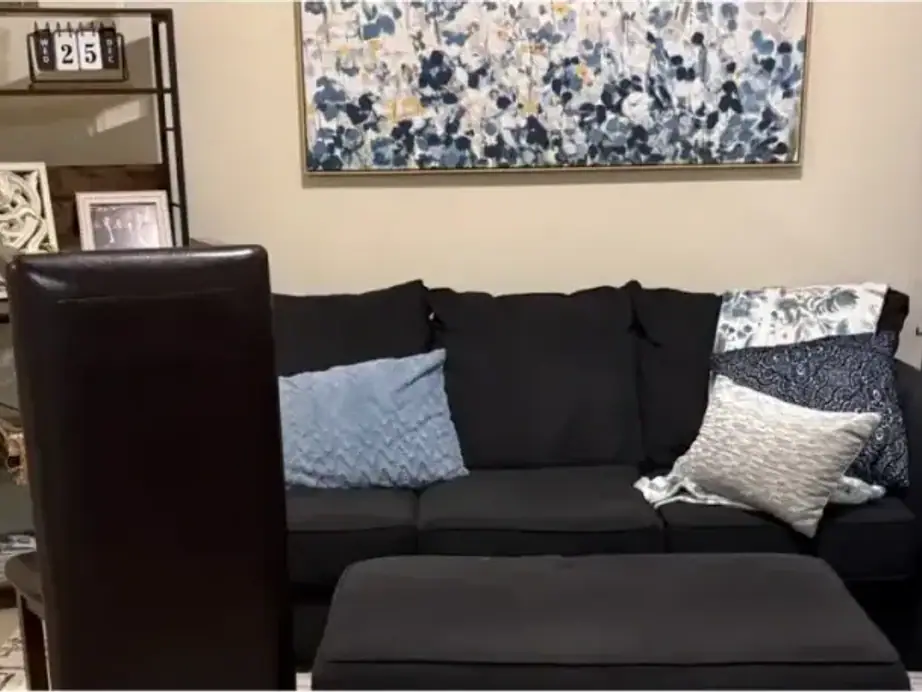 A living room with a black sofa ottoman and shelving units