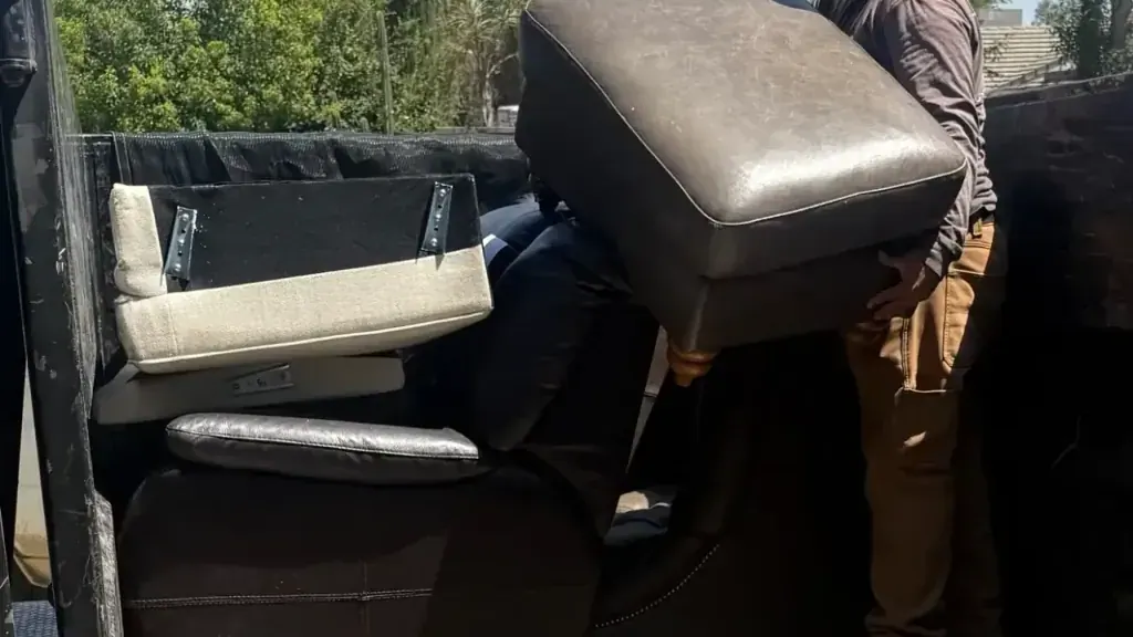 A crew member lifting a grey sofa section into the trailer