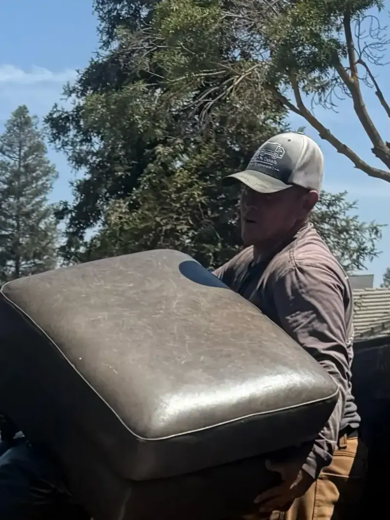 A crew member carrying an upholstered sofa piece