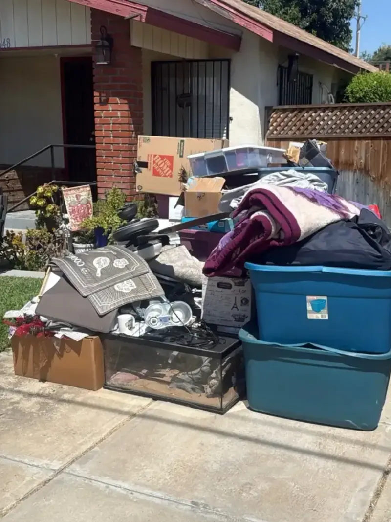 Bins boxes and household goods piled on a front walk beside a brick house