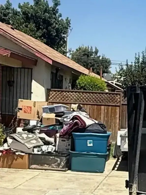 A curbside pile of household junk beside the Trash N Dash trailer