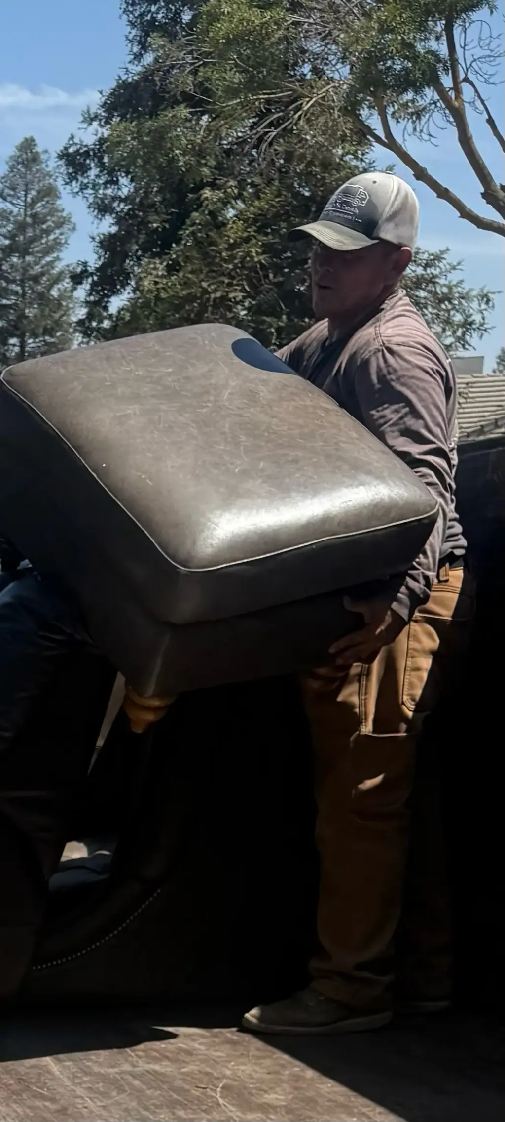 A crew member lifting an upholstered sofa piece for loading