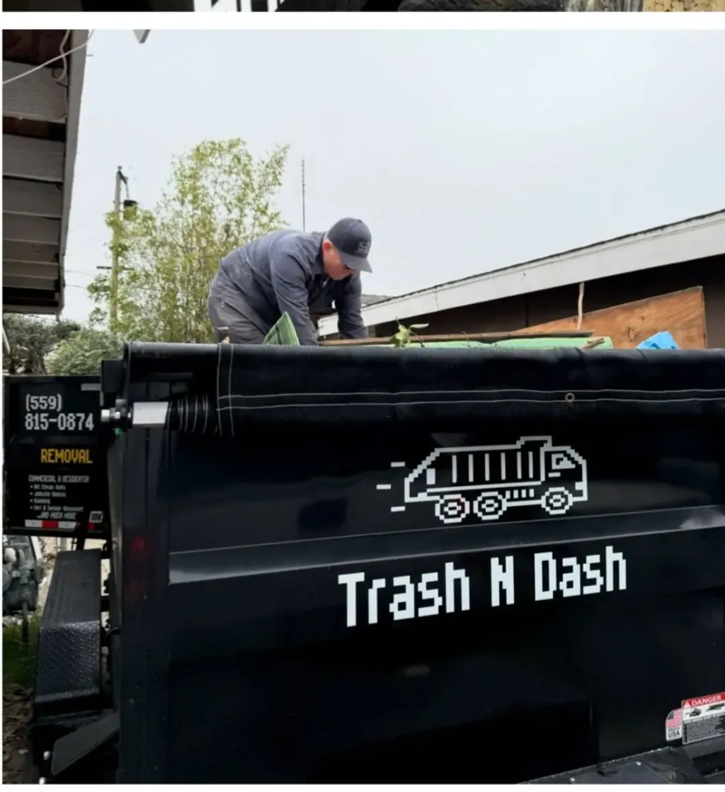 A Trash N Dash crew member loading a job into the branded dump trailer