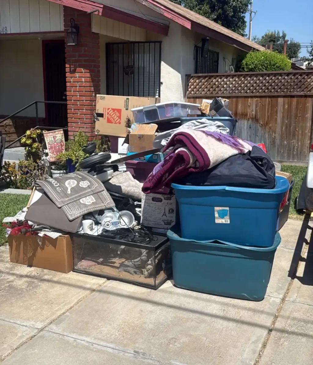 Furniture, bins and household goods stacked at the curb before removal