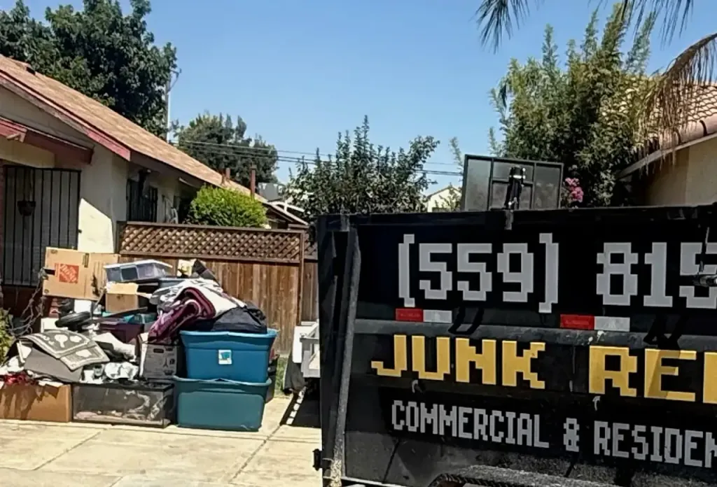 A curbside pile of household junk beside the branded Trash N Dash trailer