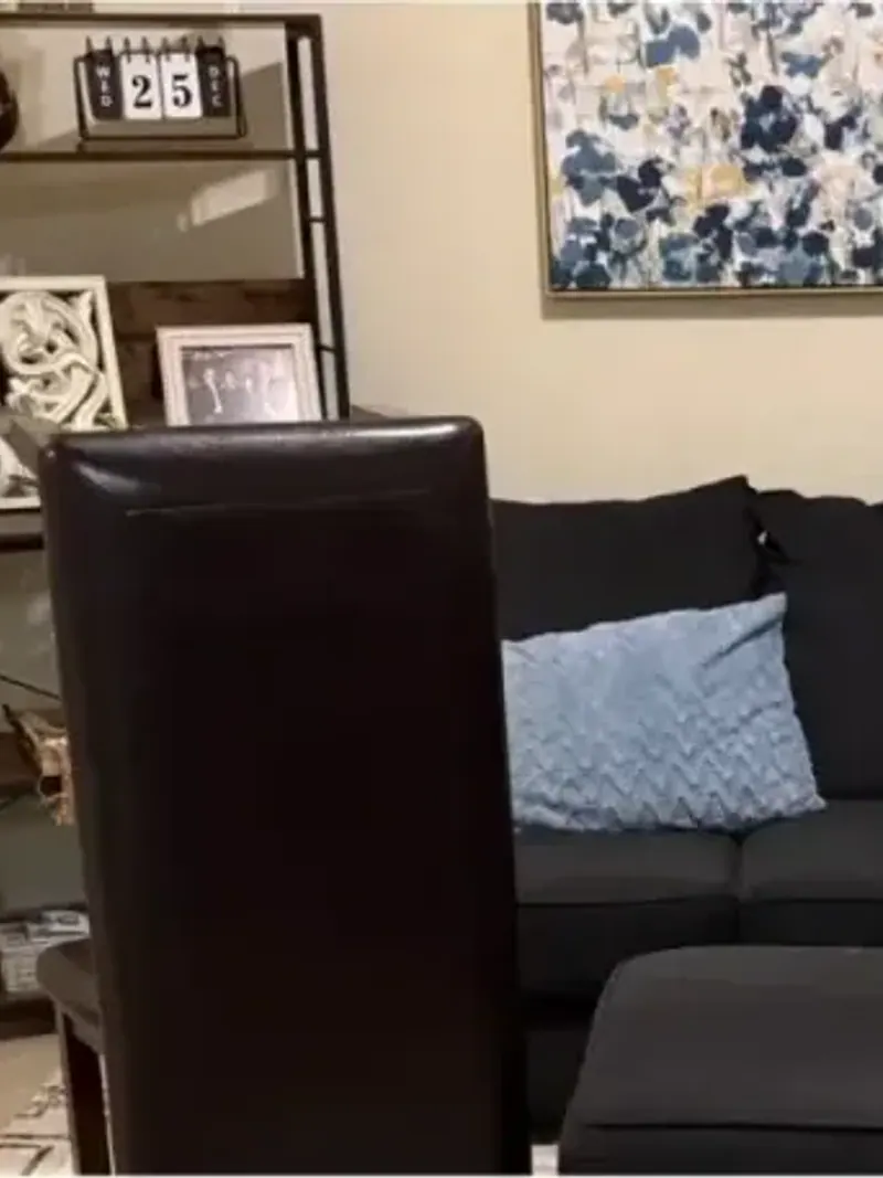 A living room with a black sofa ottoman and shelving units