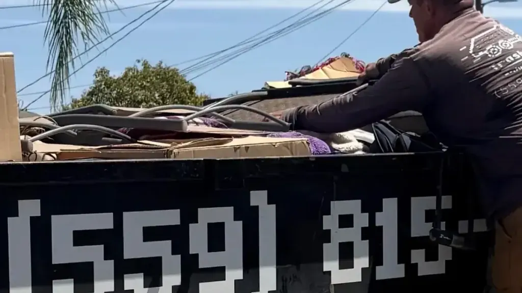 A crew member standing in the trailer loading debris under the Junk Removal lettering
