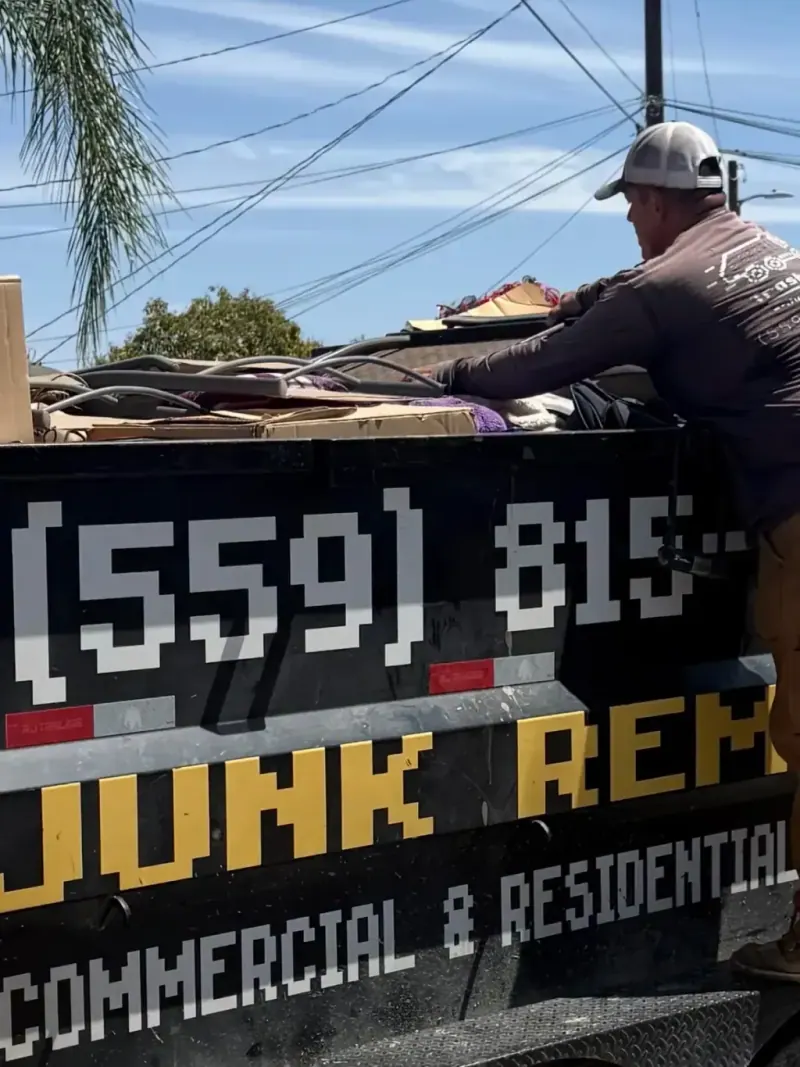 A crew member standing in the trailer loading debris under the Junk Removal lettering