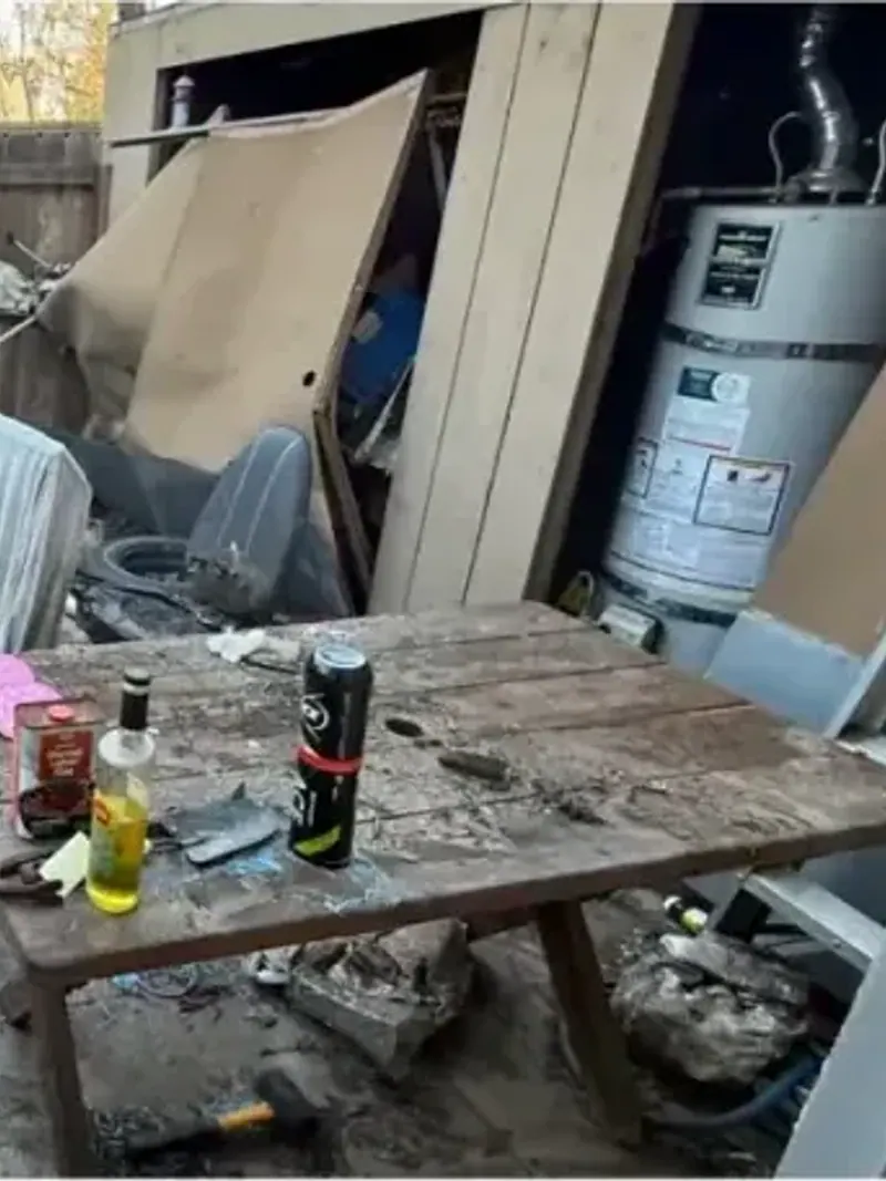 A backyard shed area with broken furniture bags and debris